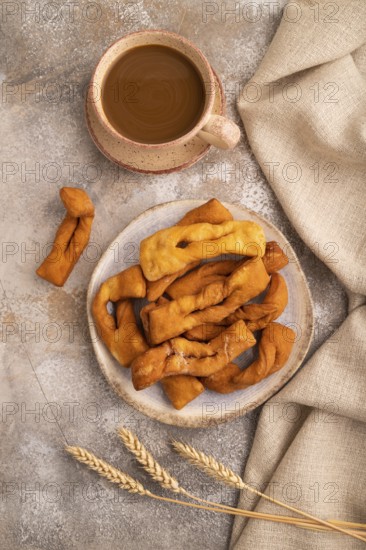 Crunchy biscuit Brushwood cookies sprinkled with powdered sugar on brown concrete background and