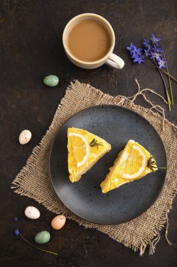 Lemon cake on black concrete background and linen textile, cup of coffee, top view, flat lay, close