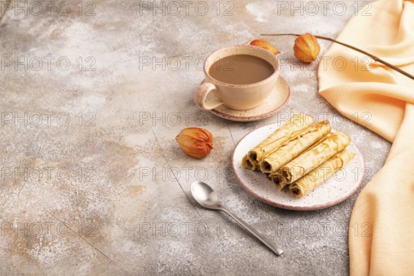 Waffles with caramel on brown concrete background and orange linen textile, cup of coffee, side