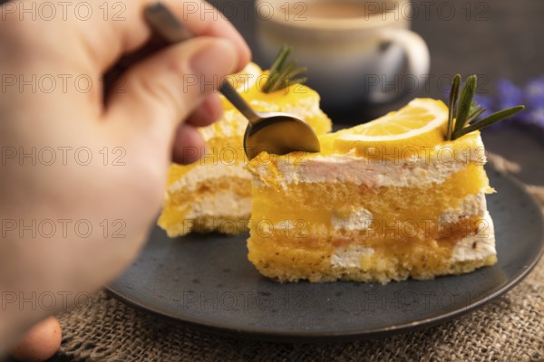 Lemon cake with hand on black concrete background and linen textile, cup of coffee, side view,