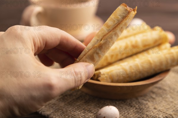Waffles with caramel with hand on brown wooden background and linen textile, cup of coffee, side
