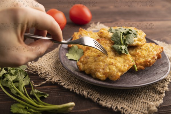 Fried crispy Chicken pancakes with hand on brown wooden background and linen textile. side view,