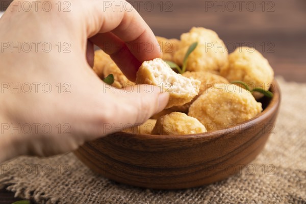 Fried crispy Chicken Nuggets with ketchup, microgreen on brown wooden background and linen textile