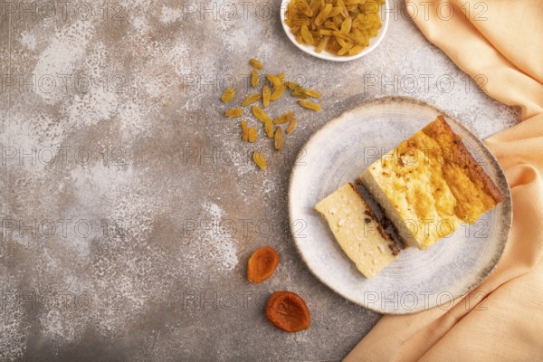 ?ottage cheese ?asserole, Curd cake, with dried apricots and raisins on brown concrete background