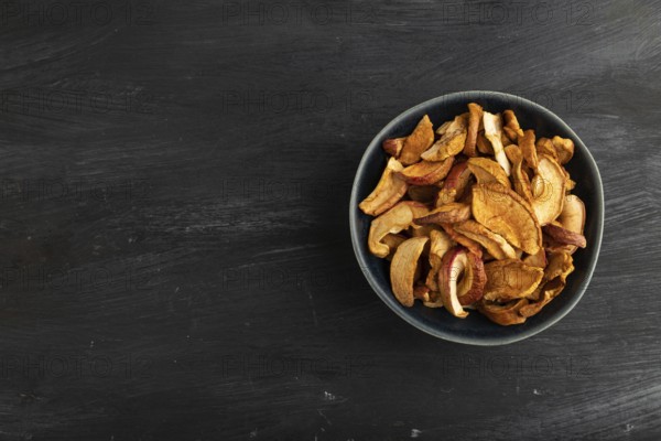 Dried Apples in ceramic bowl on black wooden background. Top view, copy space, flat lay. healthy