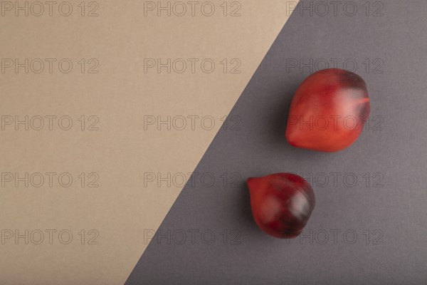 Red Heart shape tomatoes on gray and beige pastel paper background. Top view, copy space, flat lay.