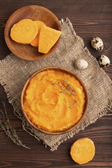 Sweet potato porridge in wooden bowl on wooden background and linen textile. Diet, healthy eating