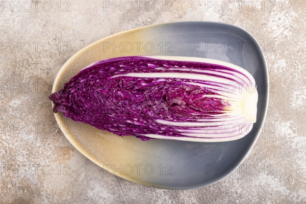 Purple Chinese cabbage on blue plate on brown concrete background, top view, flat lay, close up,