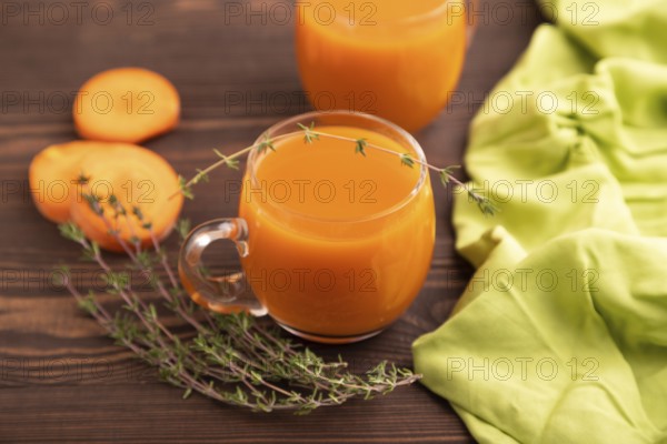 Two glasses with carrot juice, on wooden background and green textile. Diet, healthy eating concept