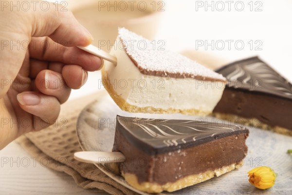 Chocolate and Vanilla Cake pops Marshmallow with hand with cup of coffee on white wooden background