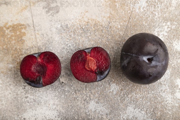 Purple Plum Cut in half on brown concrete background. Top view, flat lay, copy space. healthy food,