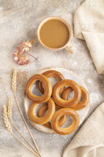Homemade Ring Bagel with cup of coffee on brown concrete background and linen textile. top view,