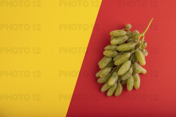 Green grapes on yellow and red paper pastel background. Top view, flat lay, copy space. healthy
