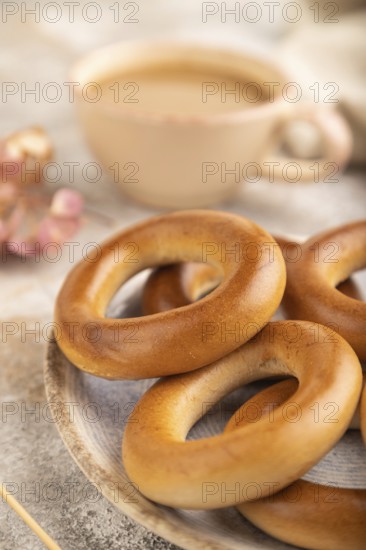 Homemade Ring Bagel with cup of coffee on brown concrete background and linen textile. side view,