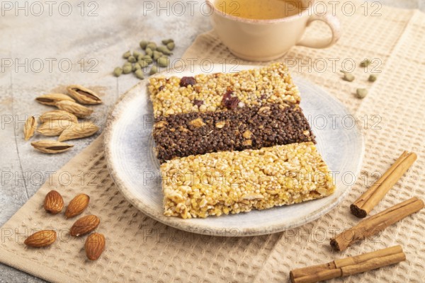 Granola bars with caramel, nuts, flakes in ceramic plate on brown concrete background, beige linen