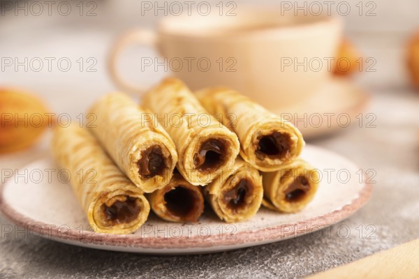 Waffles with caramel on brown concrete background and orange linen textile, cup of coffee, side