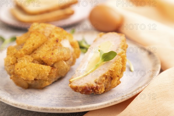 Chicken Schnitzel on blue plate with microgreen on brown concrete background and orange linen