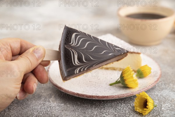 Chocolate and Vanilla Cake pops Marshmallow with hand with cup of coffee on brown concrete