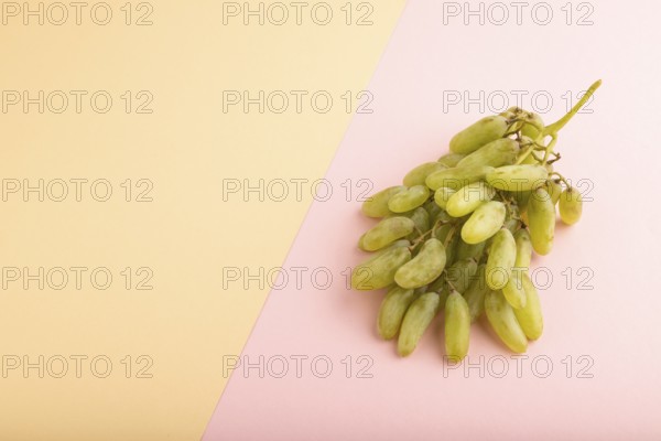 Green grapes on orange and pink paper pastel background. Side view, copy space. healthy food,