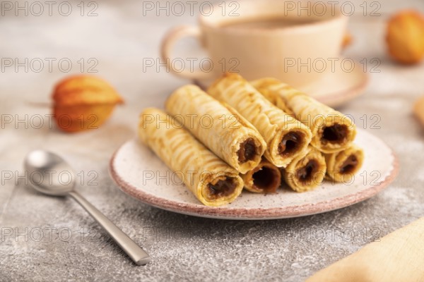 Waffles with caramel on brown concrete background and orange linen textile, cup of coffee, side