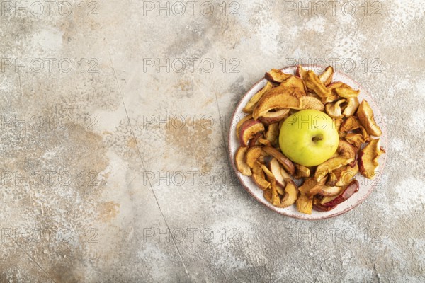 Dried Apples in ceramic bowl on brown concrete background. Top view, copy space, flat lay. healthy