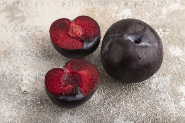 Purple Plum Cut in half on brown concrete background. Side view, close up. healthy food, vegetable,