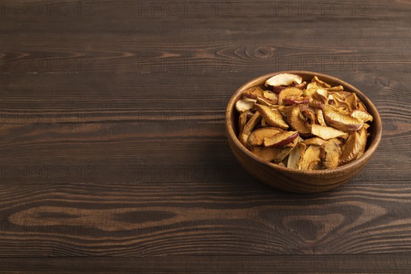 Dried Apples in wooden bowl on brown wooden background. Side view, copy space, healthy food,