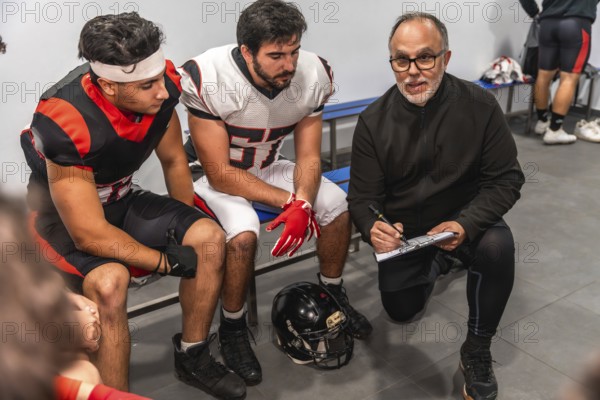 American football coach on a knee formulating game strategy and providing guidance on a clipboard