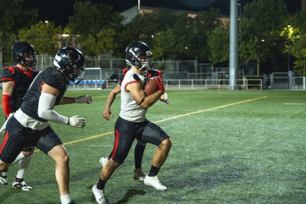 American football player is running with the ball, while teammates are blocking opponents during an