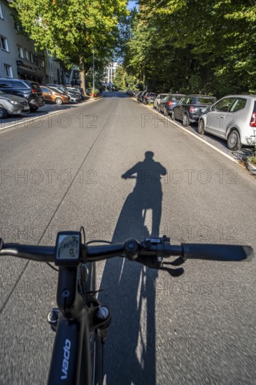 Cycling in the city, city centre street, shadow of the biker, cyclist perspective, Essen, North