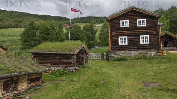 Norwegische Holzhäuser mit Gras auf den Dächern, Fahnenmast mit Norwegen-Flagge, historischer