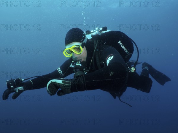 Ein Taucher in voller Ausrüstung kontrolliert unter Wasser seinen Tauchcomputer. Tauchplatz Wrack