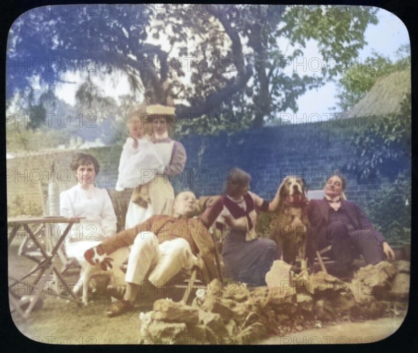 Affluent Edwardian family group men and women with nursemaid holding baby, outdoors in garden