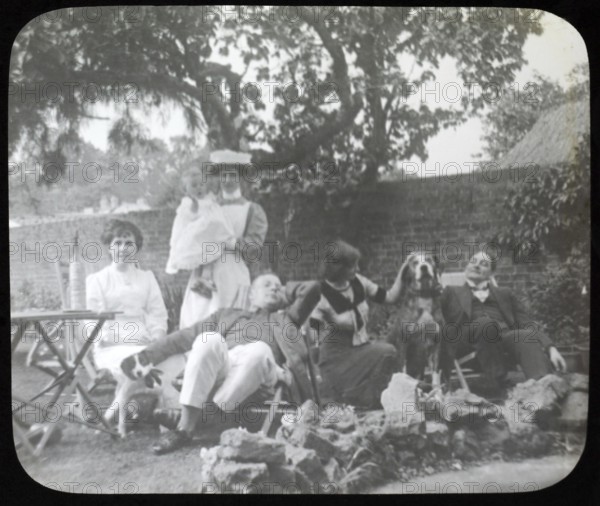 Affluent Edwardian family group men and women with nursemaid holding baby, outdoors in garden