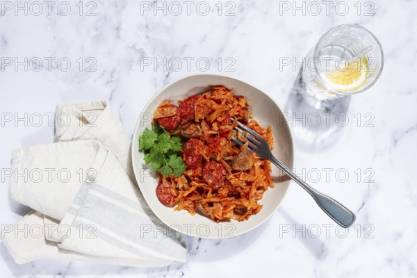 Bigos, Polish dish bigos, on a marble table, stewed meat with cabbage, chorizo sausages, mushrooms,