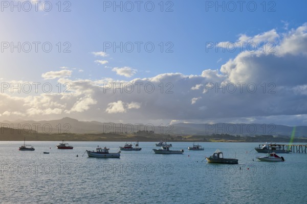 Boote auf einem sonnigen Gewässer mit einer Wolkenlandschaft im Hintergrund, Moeraki, Hampden,