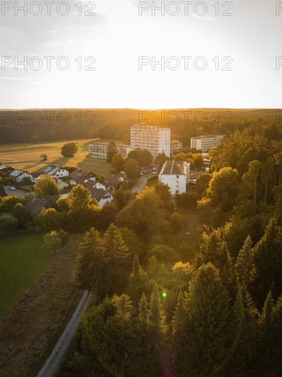 Aerial view of a village at sunset, surrounded by forests and fields, Tesla Model Y Juniper,