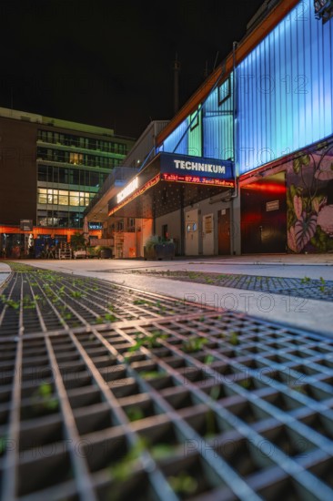 Illuminated urban scene at night with modern buildings and coloured neon lights, Tesla Model Y