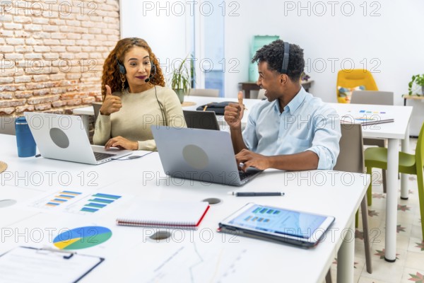 Diverse young professionals working in a modern office, wearing headsets, using laptops, and