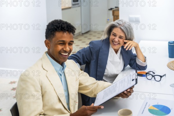 Diverse business professionals sharing a moment of laughter while reviewing documents, fostering