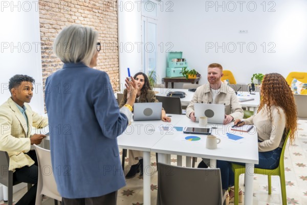 Senior professional woman presenting during a business meeting with a diverse group of young