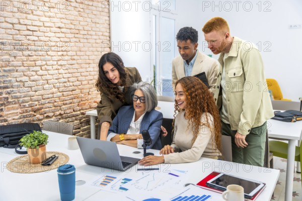 Diverse business professionals working together around a laptop, analyzing financial charts and