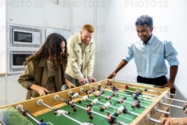 Diverse coworkers enjoying a friendly foosball game during a work break, fostering teamwork,