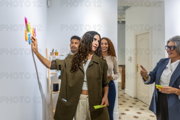 Diverse business team collaborating and brainstorming ideas, using colorful sticky notes on a wall