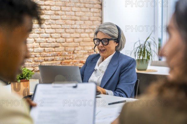 Senior businesswoman with a headset providing attentive customer service and digital support while
