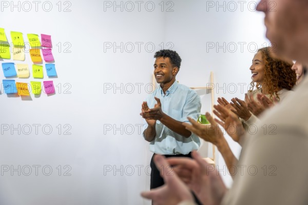 Smiling business team members are clapping, showing appreciation and recognition during a