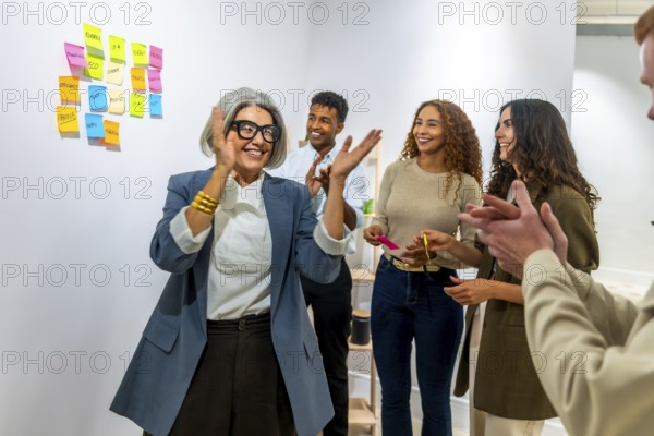 Diverse business team clapping hands, celebrating a successful achievement or project in a modern