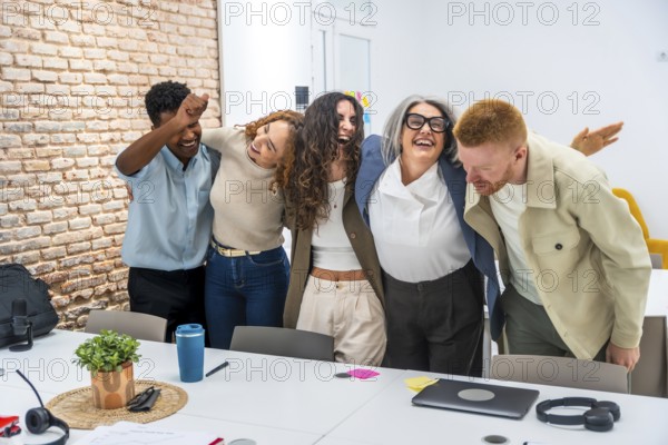 Diverse business team embracing each other excitedly, laughing and celebrating success together in