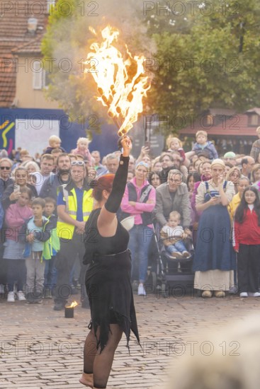 A fire show artist demonstrates her skills in front of a fascinated audience, Feuernacht,