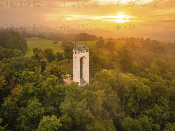 A tower in a peaceful forest landscape at sunset shows golden tones, Schönberg Tower, Pfullingen,
